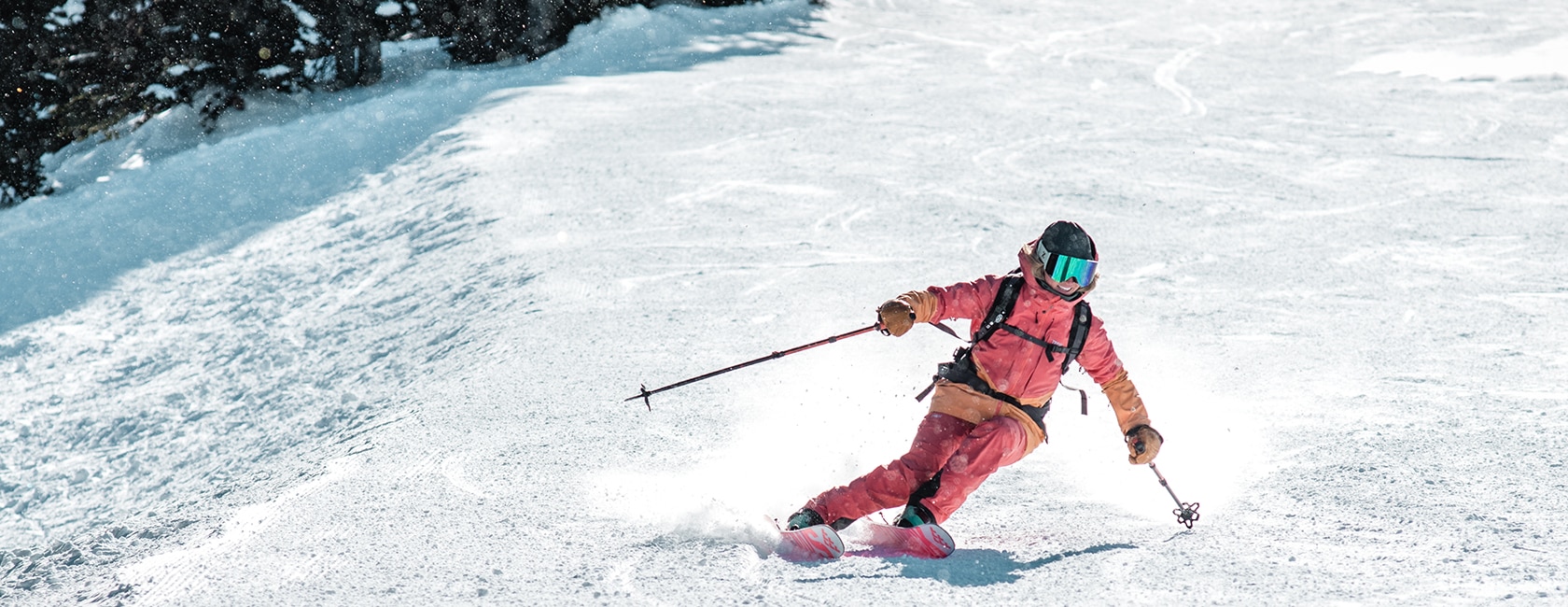 woman in pink snowsuit skiing down a hill