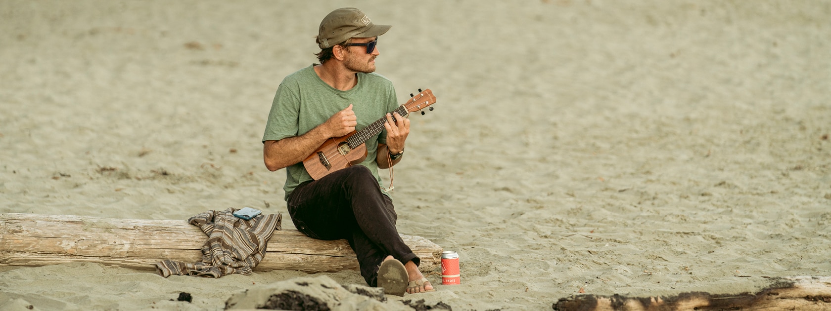 a man sitting on the beach playing the ukulele