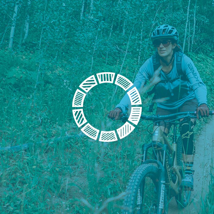 zeal optics blue light filtration icon - woman riding mountain bike on forest trail overlaid by blue hue and blue light icon