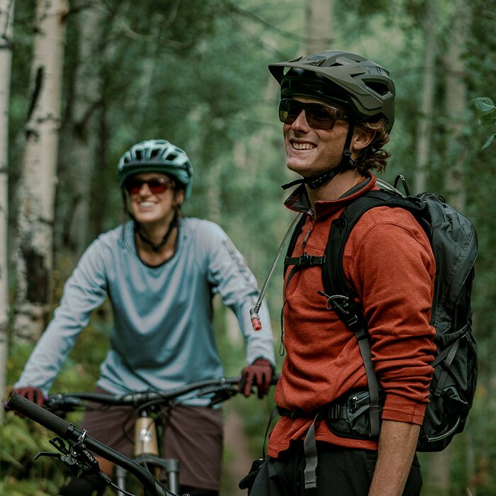 two mountain bikers wearing sunglasses on a forest trail
