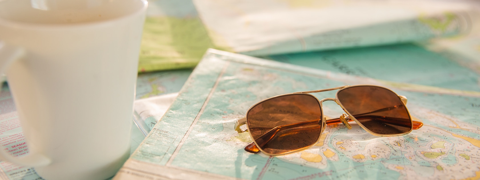 close up of zeal pescadero polarized aviator sunglasses sitting on top of map next to coffee cup