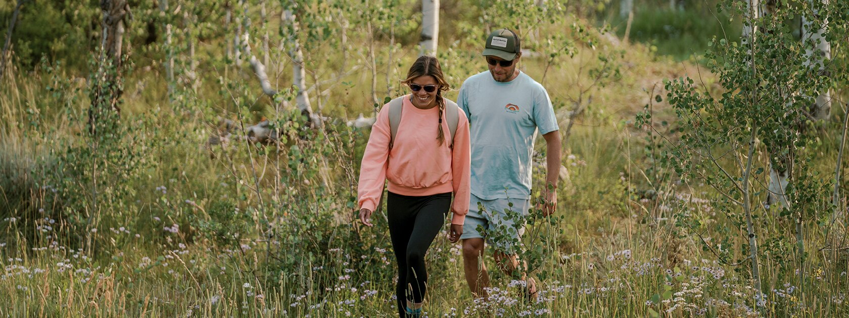 man and woman wearing polarized sunglasses walking on a grassy trail