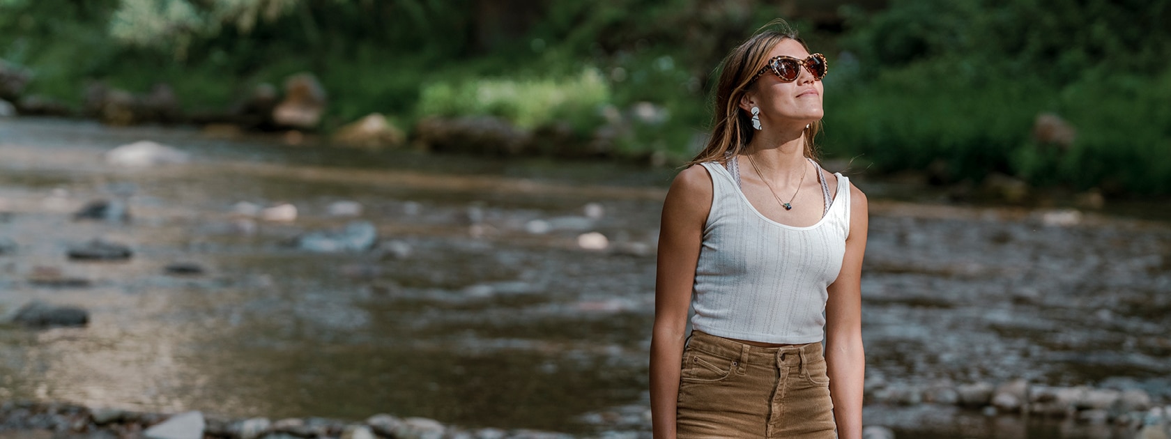woman wearing polarized sunglasses with a creek in the background