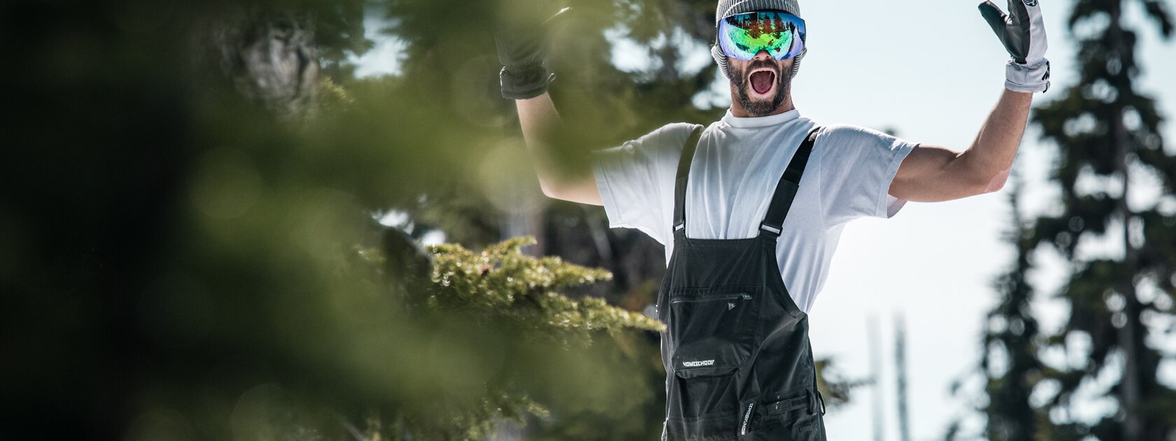 excited man in trees wearing ski goggles