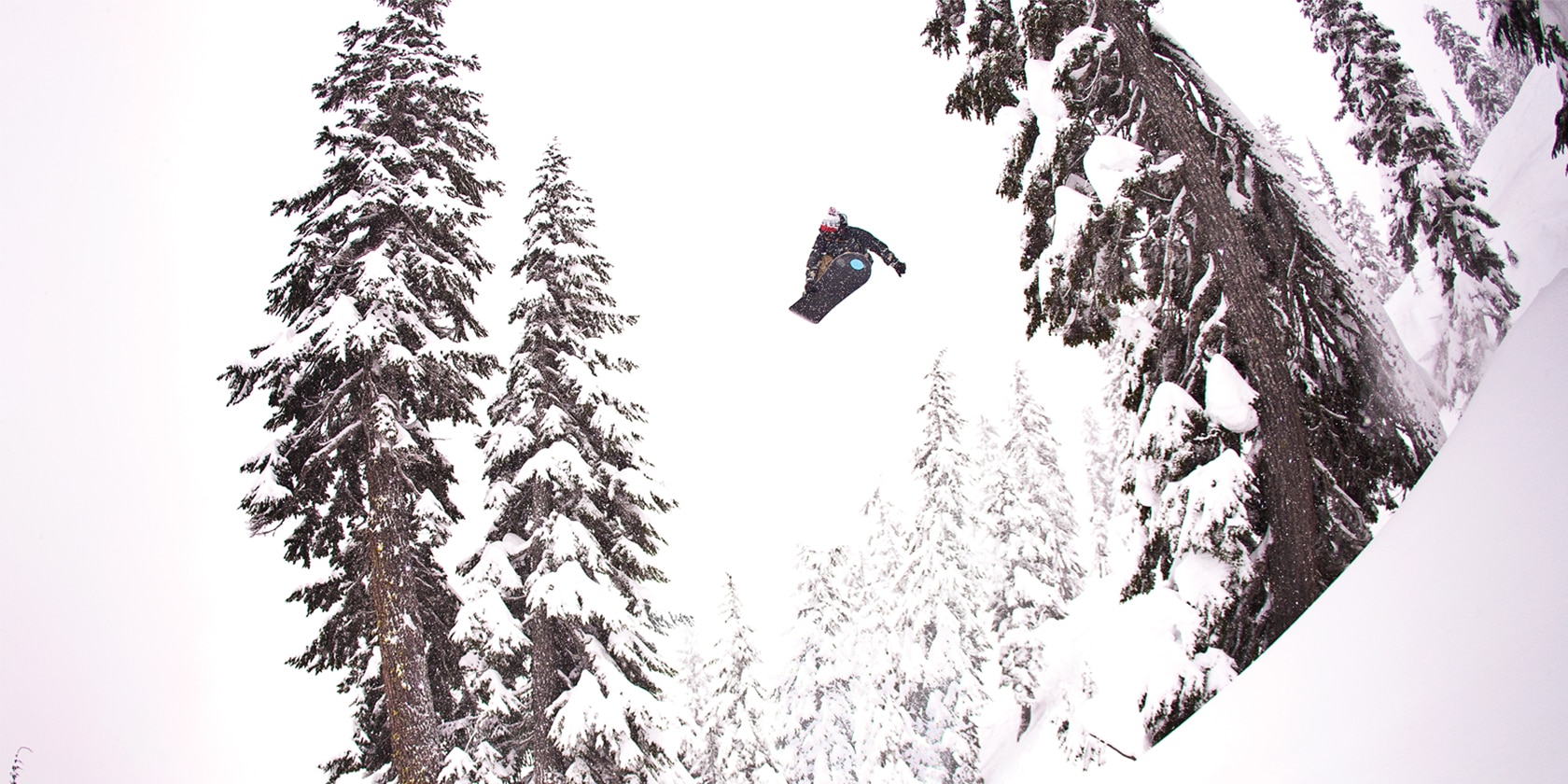 snowboarder getting huge air going down the snow covered mountain