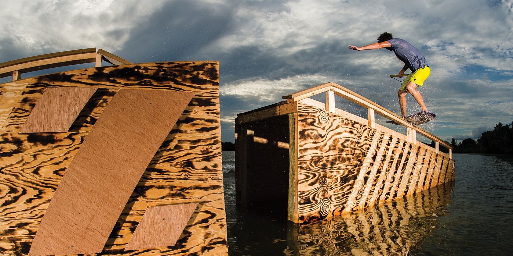 man doing tricks on his wake board on a wooden structure