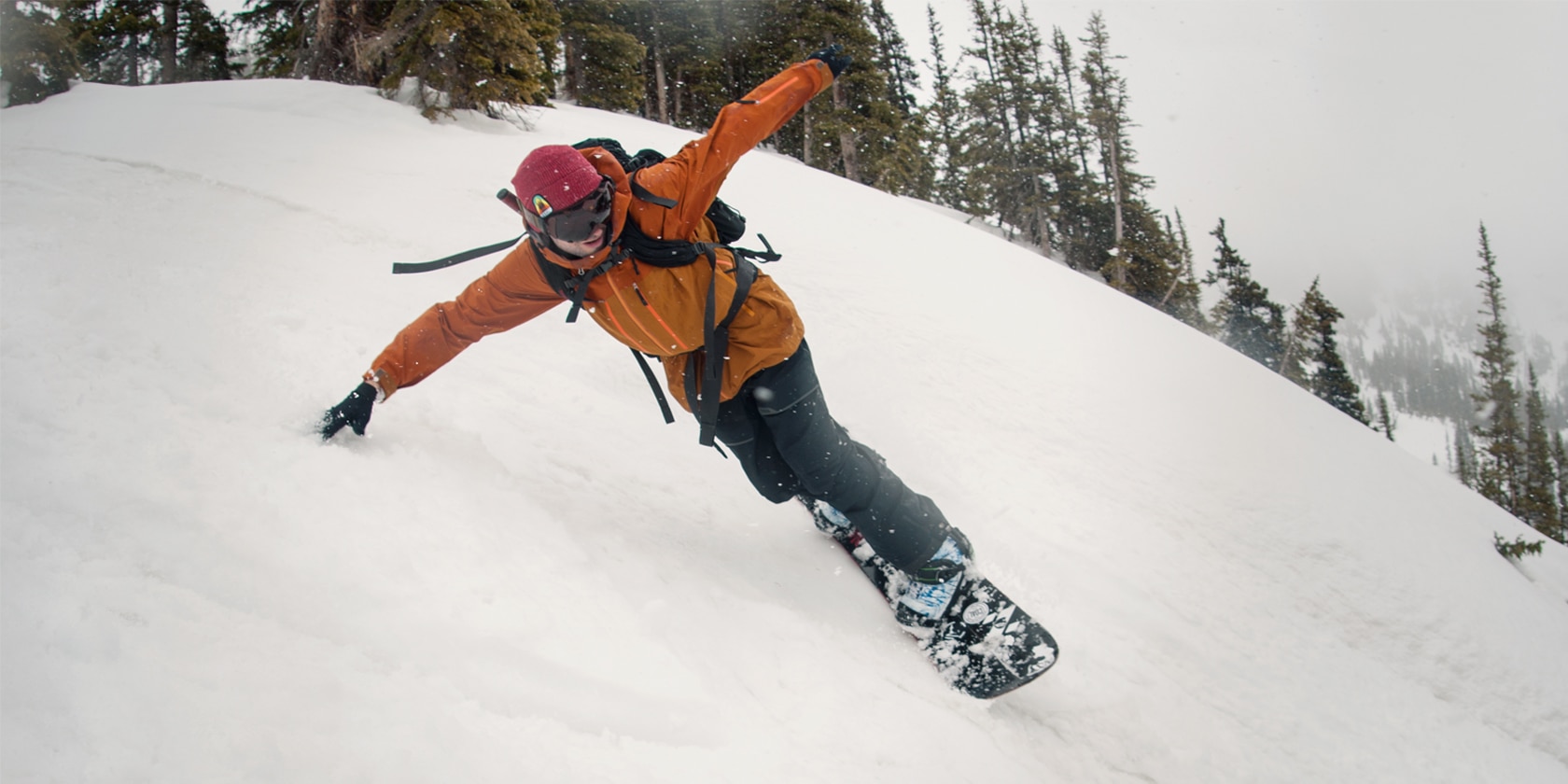 snowboarding man wildly leans with his arm extended touching snow