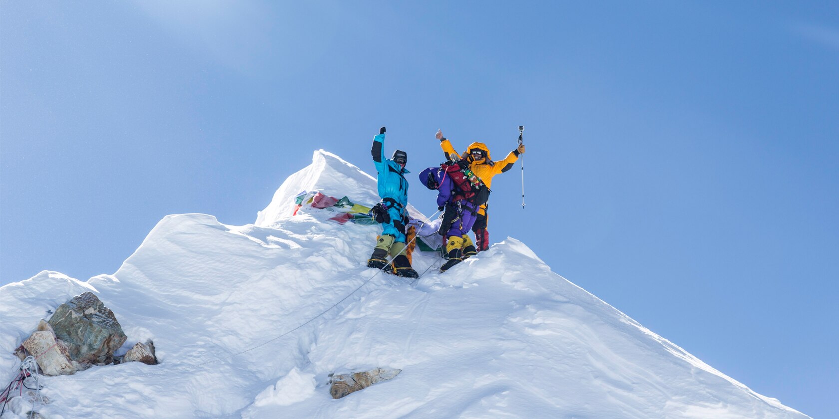 three people celibrate reaching the top of a snow covered peak