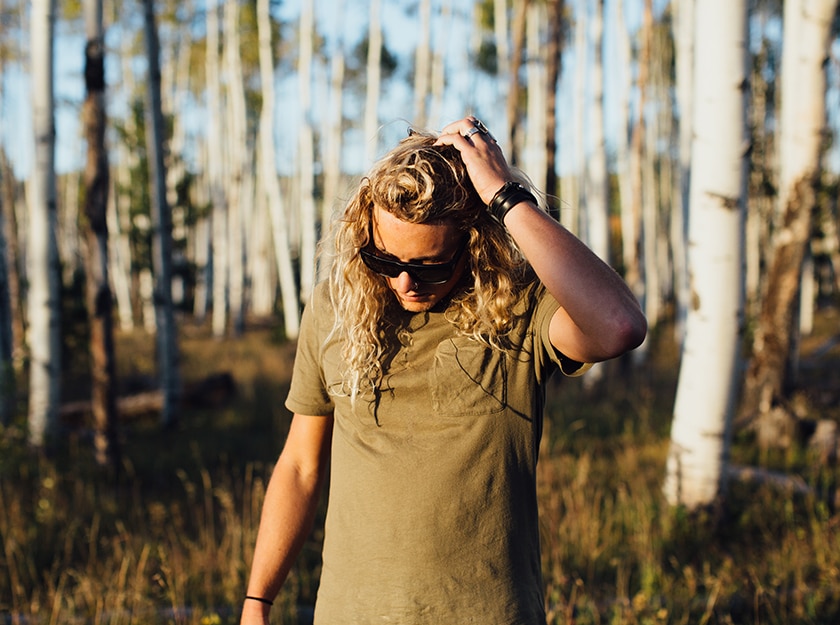 blonde curly haired man with black frame sunglasses looking down at ground