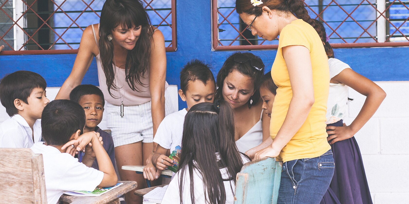 three young women reading to a group of small children