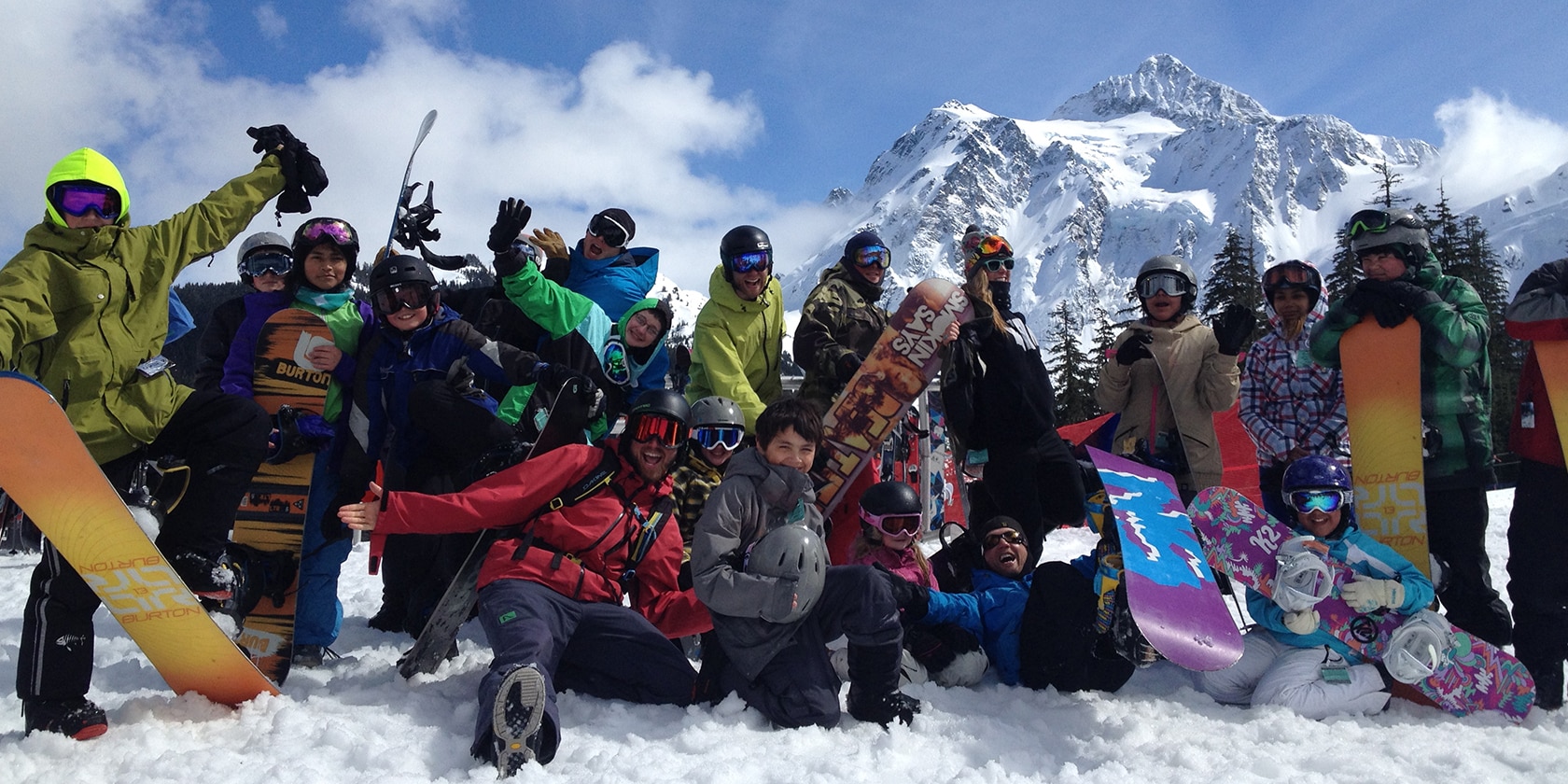 group of snowboarders posing for a picture in the snow with their snowboards