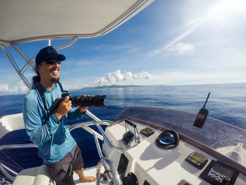 smiling man holding a camera on a boat