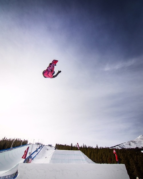 snowboarder in pink snowsuit flying through the air