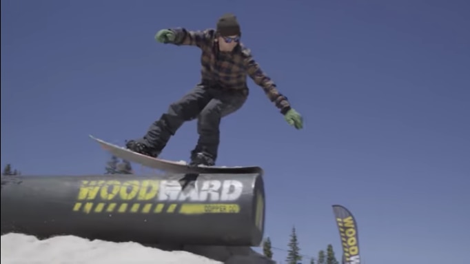 snowboarder grinding along a pipe on a snowboard course