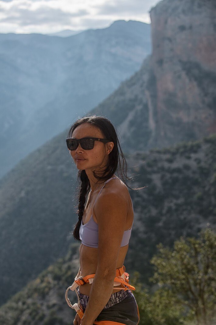Dark haired woman with sunglasses standing with mountains in background