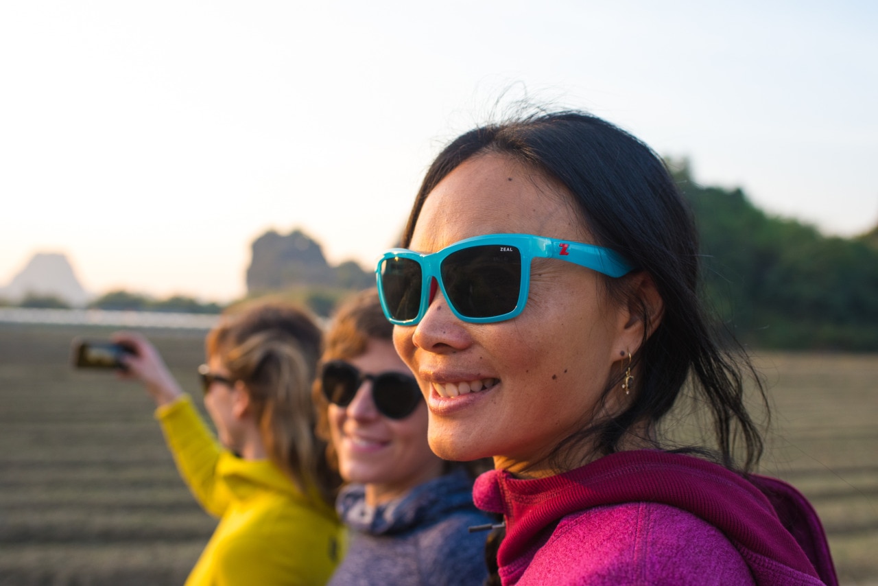 Three women wearing sunglasses as the sun sets