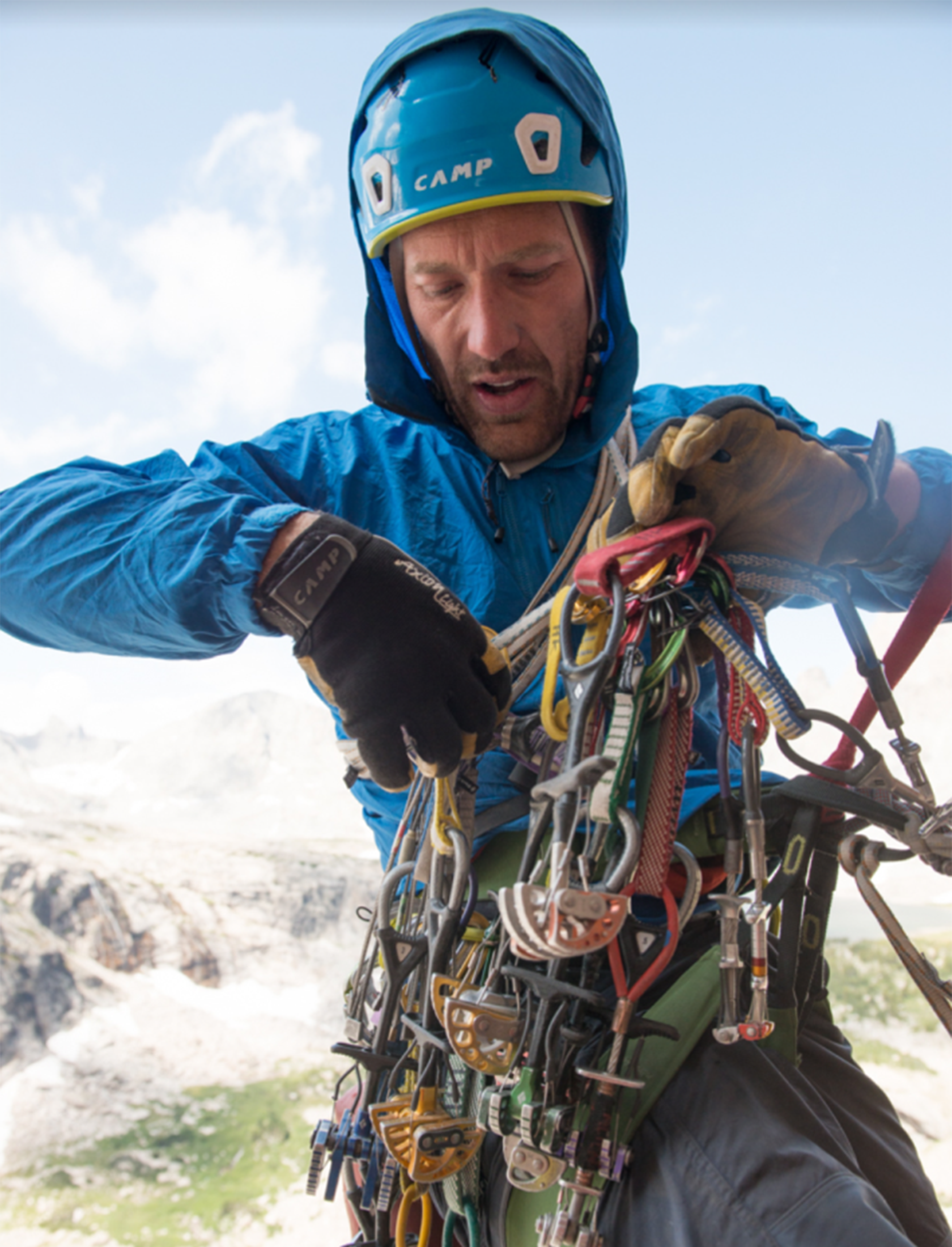 Climber in blue coat sorts through a bundle of climbing gear