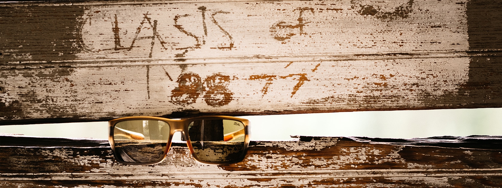a pair of Zeal Optics sunglasses propped on an opening between two wooden boards