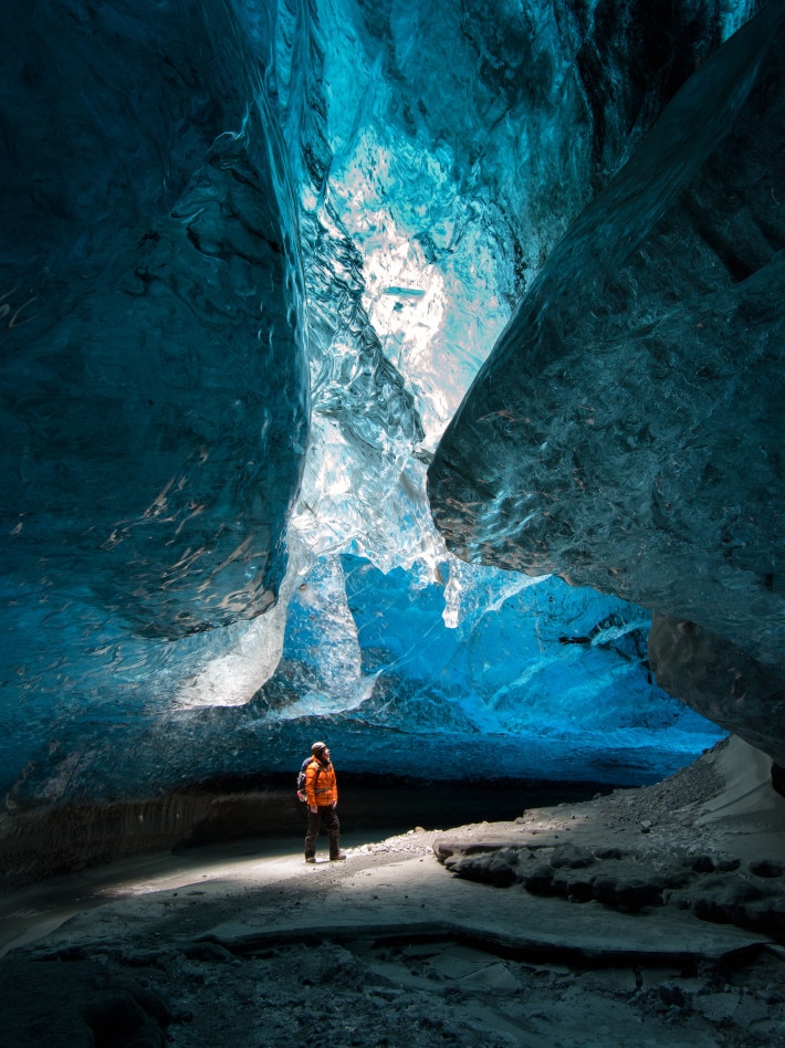 man standing under the glistening ceiling of an ice cave