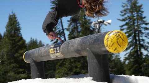 Snowboarder touching a course pipe while flipping over it