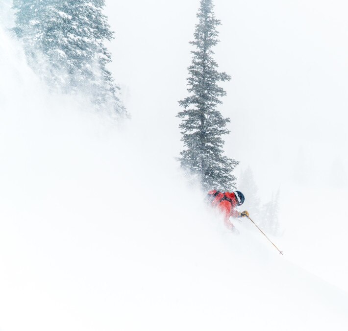 Man spraying snow as he skis down a mountain