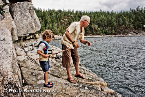 an older man and a child fishing in a lake