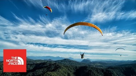 Three people paragliding over the mountains
