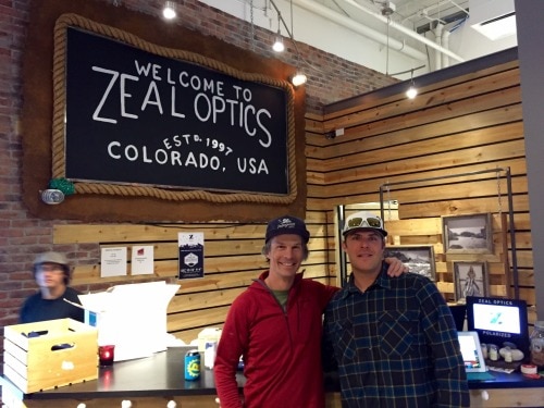 Two men smiling in the Zeal store under a Zeal Optics sign