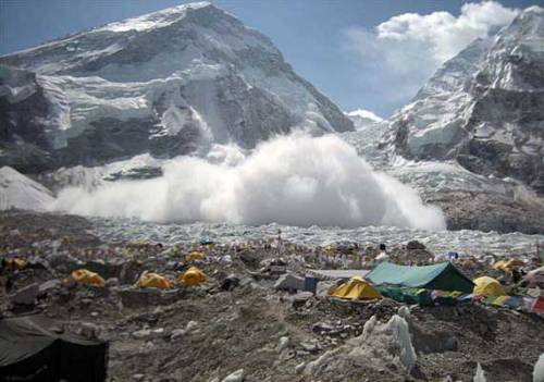 Group of camping tents at the base of a mountain with small avalanche coming towards it