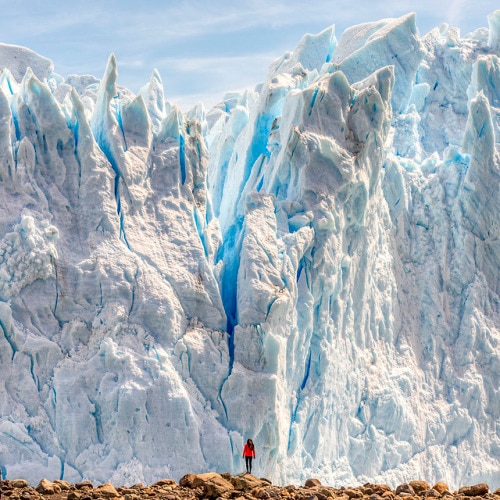 Huge glacier ice structure with a person standing in front
