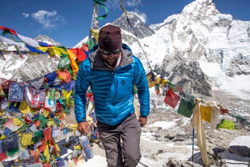 man in blue coat walking through an Everest base camp