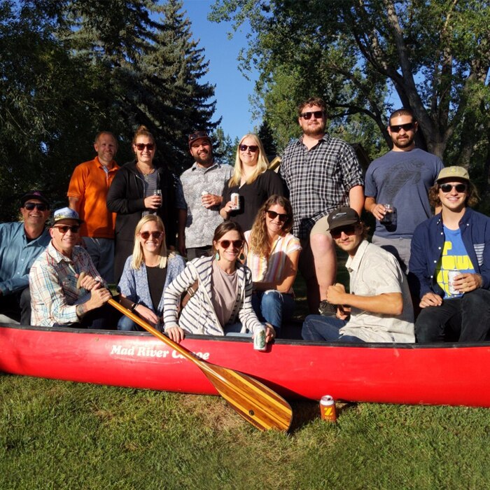 Group of people wearing sunglasses posing in a red canoe