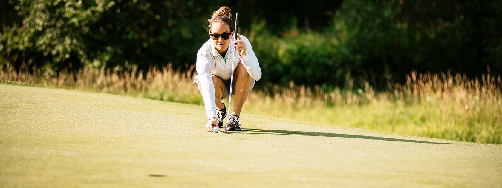 image of woman wearing zeal polarized sunglasses lining up a golf putt