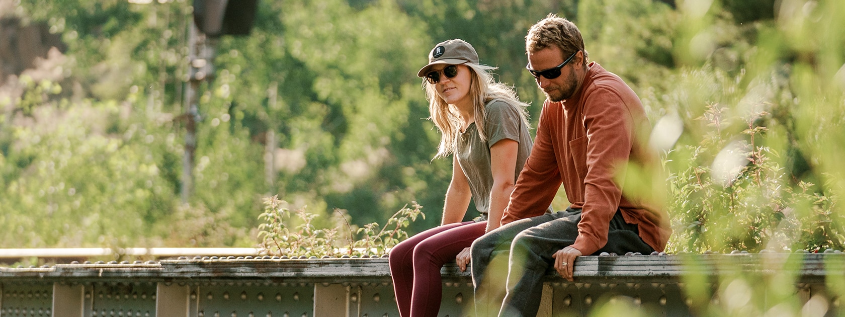 image of two people wearing zeal polarized sunglasses sitting on the edge of a bridge